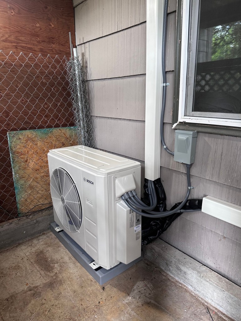 Bosch heat pump outdoor unit installed beside a house
