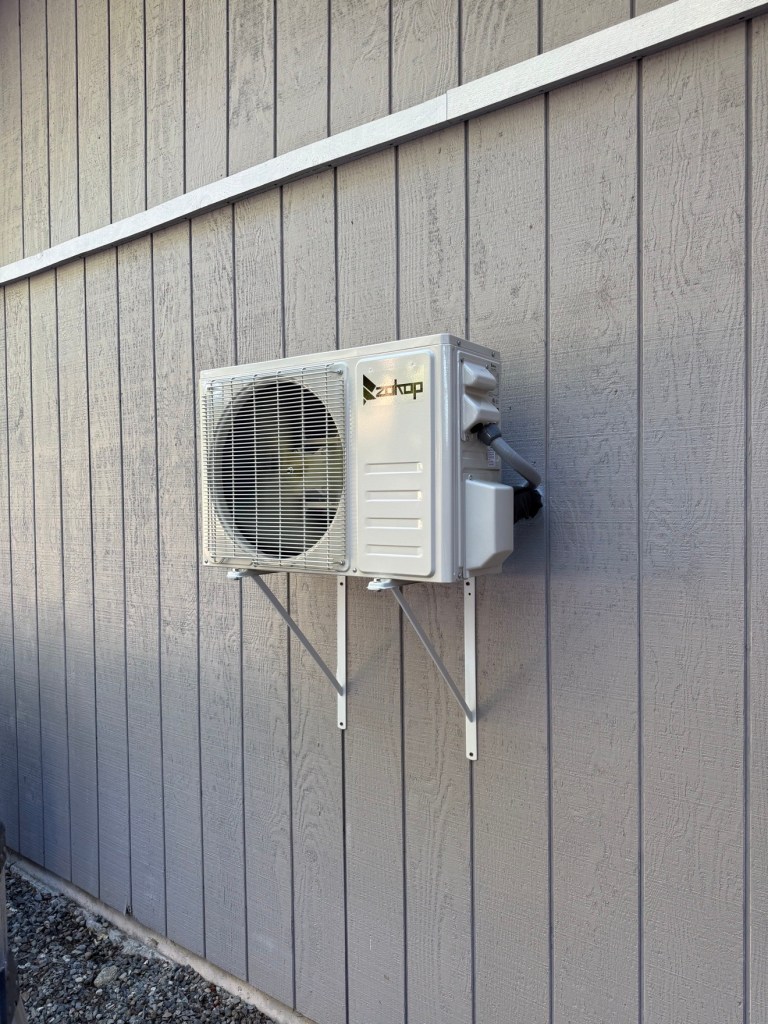 Bosch outdoor heat pump unit by a white house