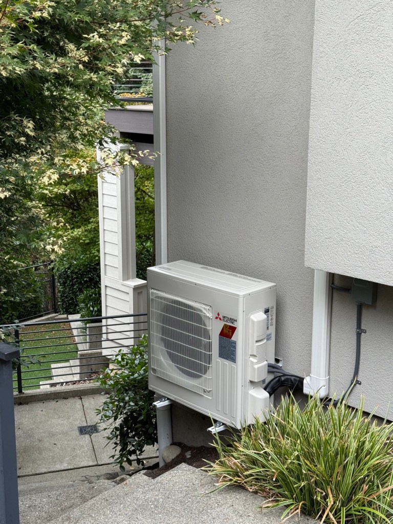 Mitsubishi Electric outdoor heat pump unit mounted beside a house
